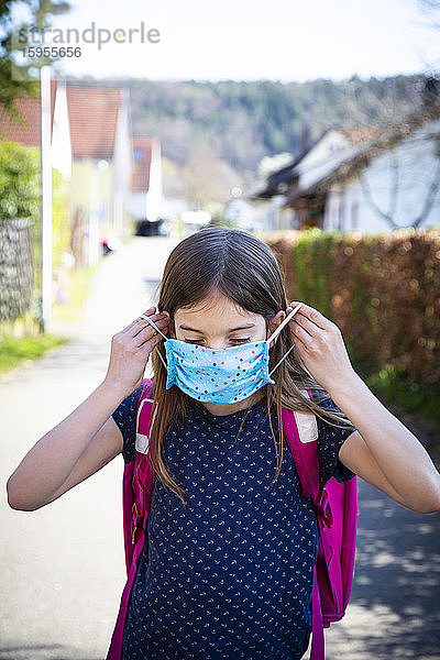 Mädchen mit selbstgemachter Schutzmaske auf dem Schulweg