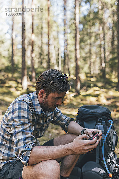 Junger Mann überprüft Navigationsgerät im Wald