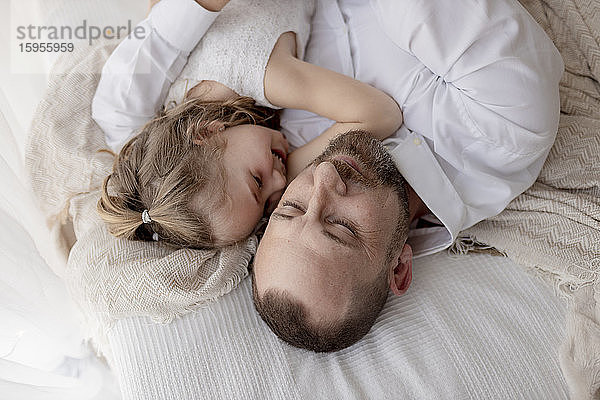 Vater und kleine Tochter ruhen gemeinsam im Bett