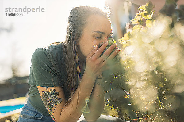 Junge Frau riecht nach Kräutern im Garten