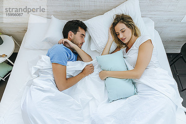 Schrägansicht eines Paares  das zu Hause auf einem Bett im Schlafzimmer schläft