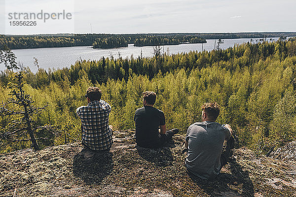 Freunde sitzen auf einem Hügel und schauen auf den See  Nykoping  Schweden