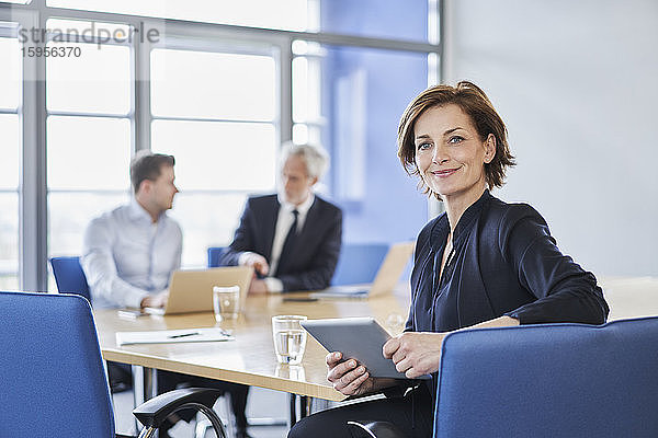 Porträt einer Geschäftsfrau mit Tablett während einer Besprechung im Büro