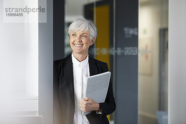 Porträt einer lächelnden älteren Geschäftsfrau  die aus der Ferne betrachtet