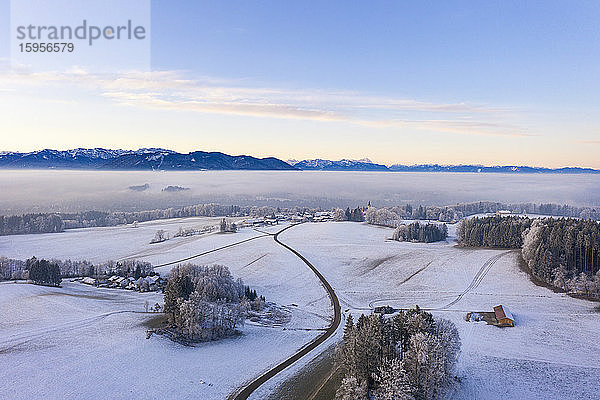 Deutschland  Bayern  Hechenberg  Drohnenansicht eines schneebedeckten Dorfes in der Nebeldämmerung