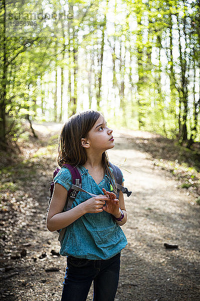 Bildnis eines Mädchens mit Rucksack auf einem Waldweg stehend