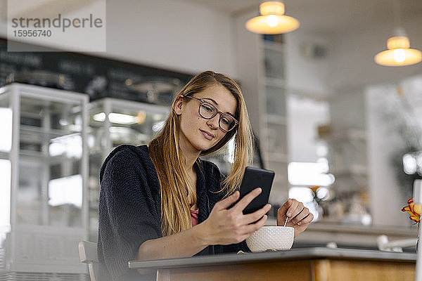 Junge Frau benutzt Smartphone in einem Café