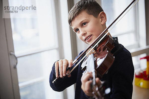 Junge spielt Geige während einer Unterrichtsstunde