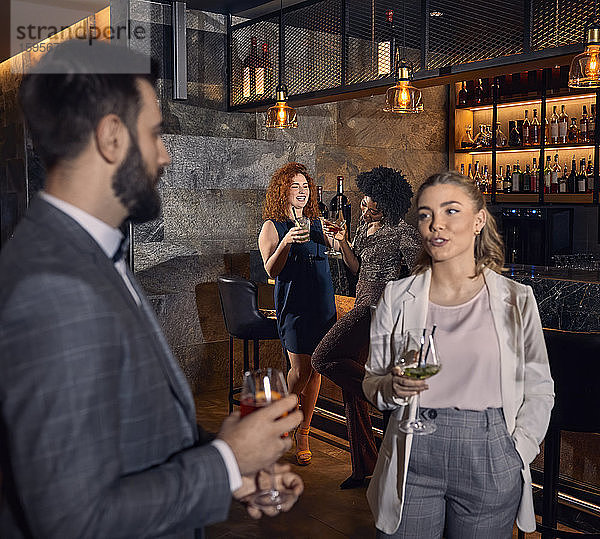 Mann und Frau unterhalten sich mit Cocktails in einer Bar