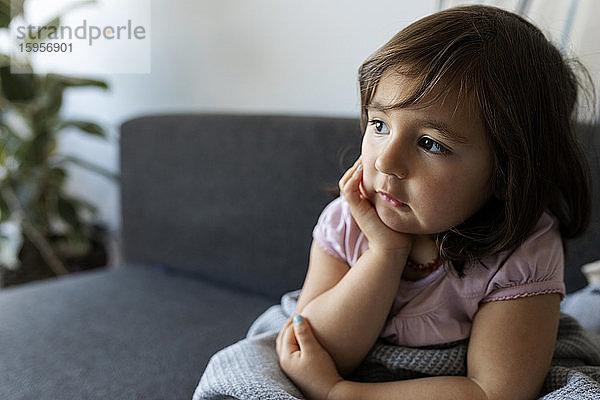 Porträt eines Mädchens  das zu Hause auf einer Couch sitzt
