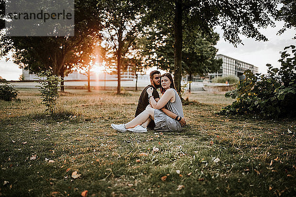 Junges Paar sitzt bei Sonnenuntergang in einem Park