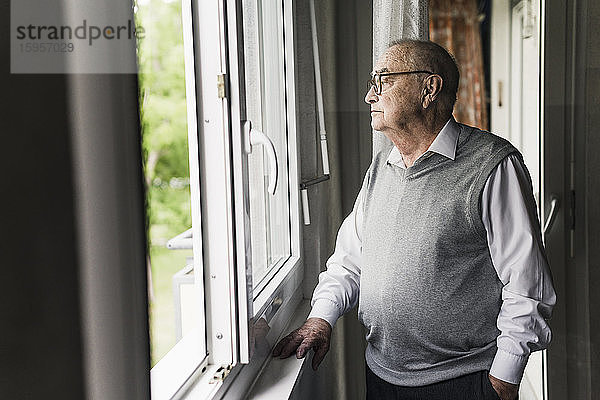 Nachdenklicher älterer Mann schaut aus dem Fenster