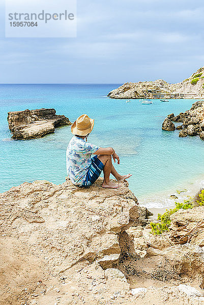Mann sitzt auf einer Klippe und schaut aufs Meer  Ibiza  Spanien