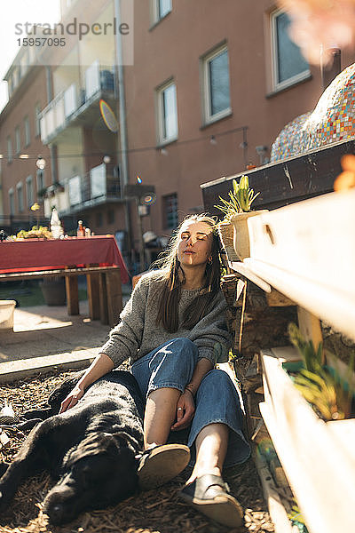 Entspannte junge Frau mit Hund im Garten