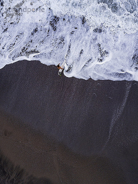 Indonesien  Bali  Pererenan Beach  Luftaufnahme eines einsamen Surfers am schwarzen Küstenstrand