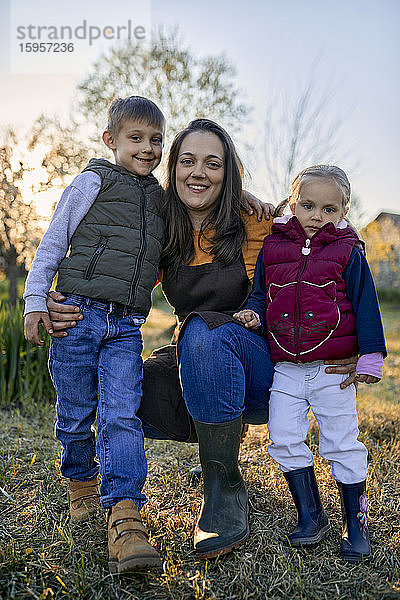Porträt einer glücklichen Mutter mit zwei Kindern im Garten