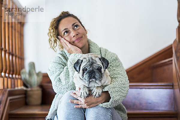 Frau sitzt auf der Treppe  mit Mops auf dem Schoss