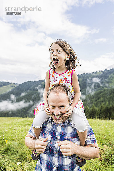 Glücklicher Vater trägt Tochter auf den Schultern auf einer Wiese in den Bergen  Achenkirch  Österreich