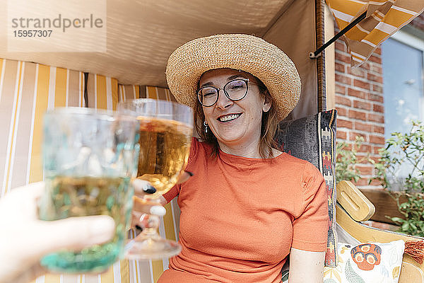 Porträt einer glücklichen reifen Frau auf der Terrasse  die mit einem Glas Limonade anstößt