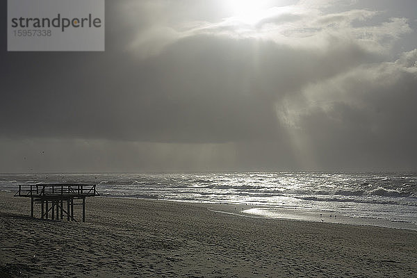 Deutschland  Schleswig-Holstein  Westerland  Sonnenlicht durchdringt Sturmwolken über dem Küstenstrand der Nordsee