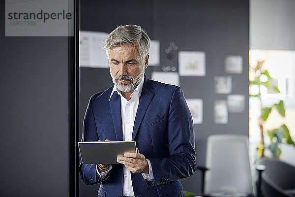 Reifer Geschäftsmann benutzt Tablet im Büro