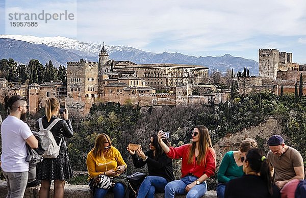 Touristen fotografieren sich mit der maurischen Stadtburg Alhambra  Nasriden-Paläste  Palast Karl V.  hinten schneebedeckte Sierra Nevada  Granada  Andalusien  Spanien  Europa