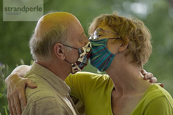 Küssen mit Atemschutzmaske während Corona-Krise  älteres Ehepaar  Deutschland  Europa