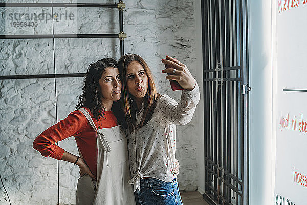 Zwei mittelgroße erwachsene Frauen posieren für Selfie auf Smartphone in ihrem neuen Laden