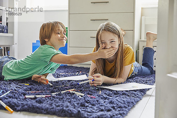 Junge und Mädchen liegen auf blauem Teppich  Zeichnung mit Farbstiften.