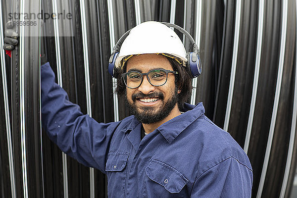 Bärtiger Mann mit Brille und weißem Schutzhelm bei der Arbeit auf der Baustelle.