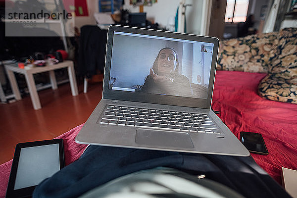 Mann im Online-Chat mit einer Freundin mit Laptop  während er sich während der Corona-Krise selbst isoliert.