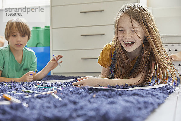 Junge und Mädchen liegen auf blauem Teppich  Zeichnung mit Farbstiften.