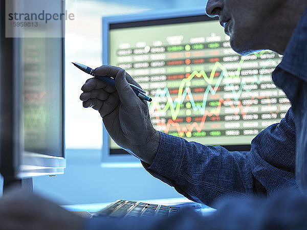 Nahaufnahme eines Börsenhändlers  der Aktienkursdaten auf dem Bildschirm analysiert.