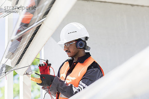 Männlicher Ingenieur mit Schutzhelm und Gehörschutz bei der Arbeit auf der Baustelle.