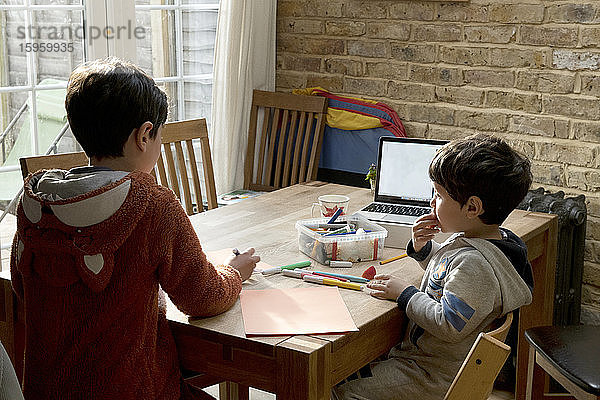 Zwei Brüder  die an einem Tisch saßen  zeichneten mit Filzstiften  Zeichnungen  um dem Gesundheitsdienst des NHS zu danken.