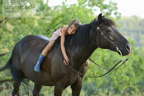 Mädchen liegt auf einem Pferd