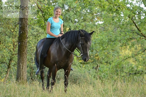Lächelndes Mädchen reitet auf einem Pferd