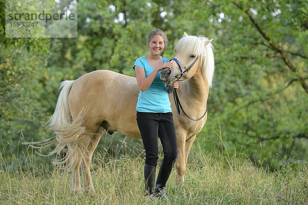 Lächelndes Mädchen mit Pferd auf einer Wiese