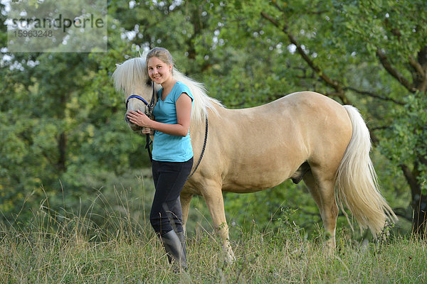 Lächelndes Mädchen mit Pferd auf einer Wiese