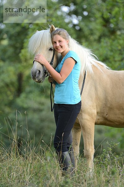 Lächelndes Mädchen mit Pferd auf einer Wiese