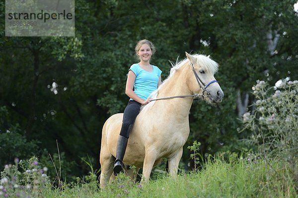 Lächelndes Mädchen reitet auf einem Pferd