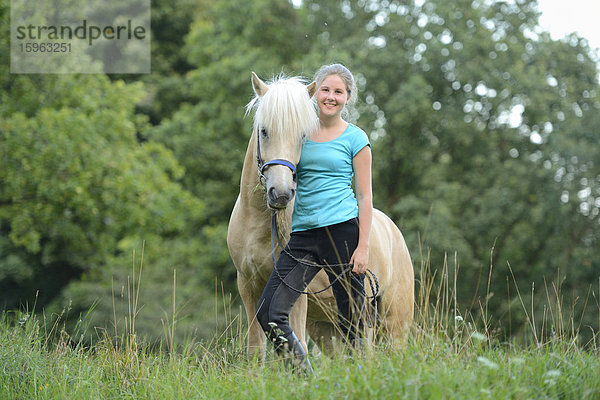 Lächelndes Mädchen mit Pferd auf einer Wiese