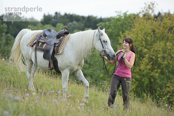 Lächelnde Teenagerin mit Pferd auf einer Wiese