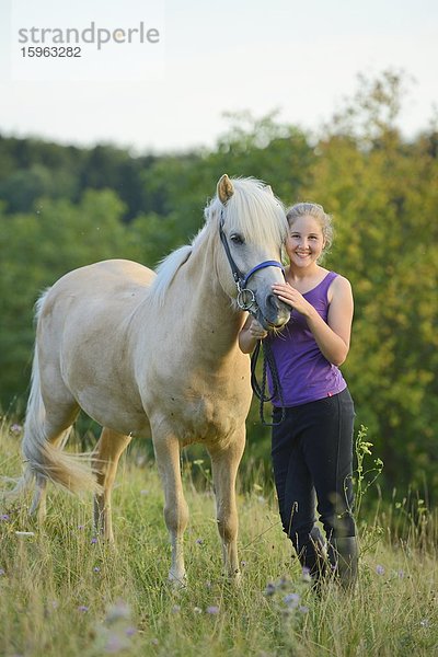 Lächelndes Mädchen mit Pferd auf einer Wiese