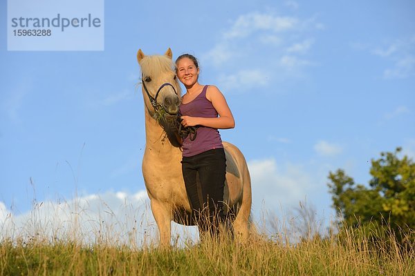 Lächelndes Mädchen mit Pferd auf einer Wiese