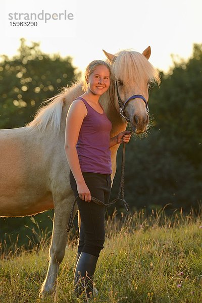 Lächelndes Mädchen mit Pferd auf einer Wiese