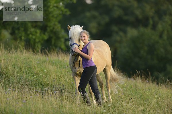 Lächelndes Mädchen mit Pferd auf einer Wiese