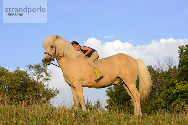Mädchen sitzt auf einem Pferd