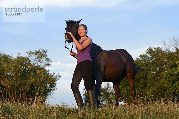 Lächelndes Mädchen mit Pferd auf einer Wiese