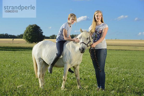 Zwei Mädchen mit Pferd auf einer Wiese